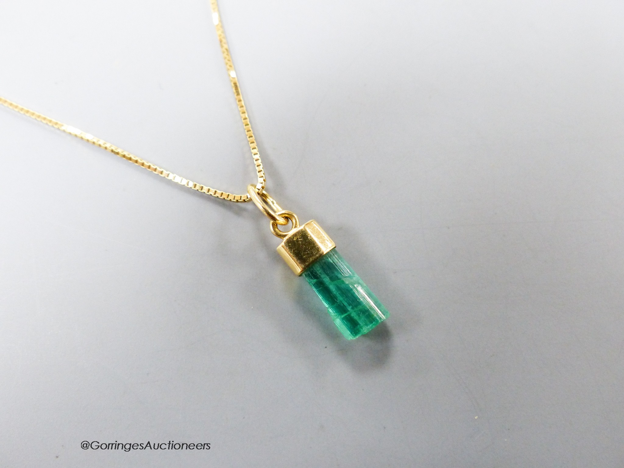 A modern Italian 750 yellow metal and emerald set pendant, 13mm, on a finelink chain, 39cm, gross weight 2.7 grams(stone a.f.).